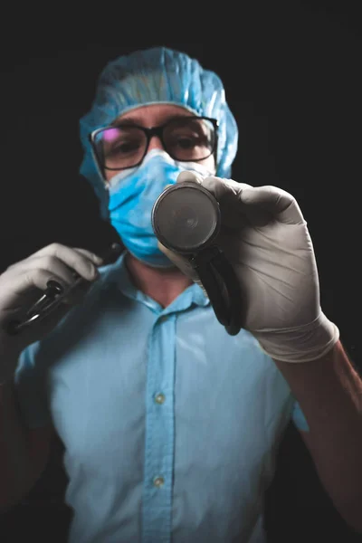 Medical doctor, nurse, surgeon, psychologist working with protective mask, glasses and gloves helping people in the days of panic, pandemic - studio shot on black background.