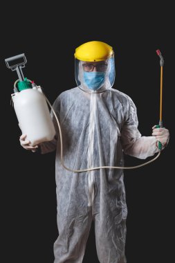 Koruyucu antiviral maskesi, giysisi, miğferi ve kimyasal dezenfekte spreyi olan kişiler ev izolasyonunda..
