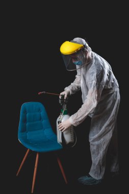 Koruyucu antiviral maskesi, giysisi, miğferi ve kimyasal dezenfekte spreyi olan kişiler ev izolasyonunda..