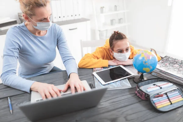 Child home studying education, homeschooling, with private tutor / mother with protective mask in the time of viruses, flu and seasonal pandemic, healthy approach in social contact.