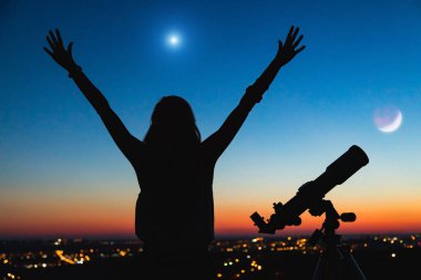 Bir kadın silueti ve alacakaranlık gökyüzü ile teleskop.