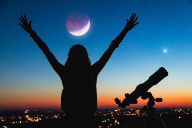 Bir kadın silueti ve alacakaranlık gökyüzü ile teleskop.