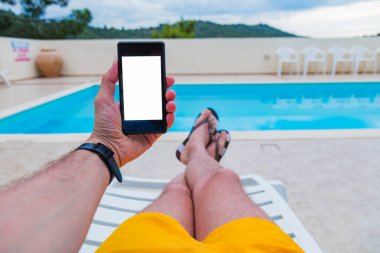 Yüzme havuzuyakınında cep telefonu kullanan adam.