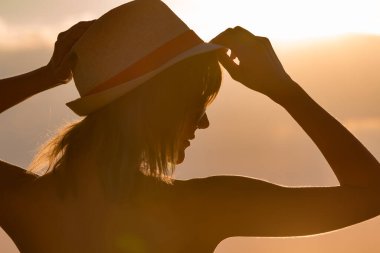 Gün batımında okyanus / deniz kıyısında eğlenen bir kızın silueti..