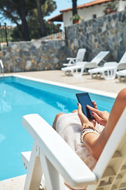 Yüzme havuzu yakınında cep telefonu kullanan genç kadın.