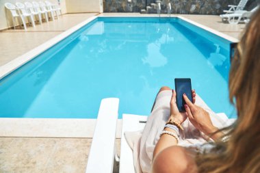 Yüzme havuzu yakınında cep telefonu kullanan genç kadın.