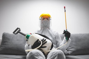 Koruyucu antiviral maskesi, giysisi, miğferi ve kimyasal dezenfekte spreyi olan kişiler ev izolasyonunda..
