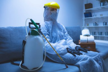 Klozet kağıdı stoğu ve koruyucu antiviral maskesi olan kişi, kask, kimyasal dezenfekte spreyi ve ev izolasyonu şişesi..