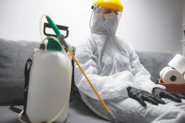 Klozet kağıdı stoğu ve koruyucu antiviral maskesi olan kişi, kask, kimyasal dezenfekte spreyi ve ev izolasyonu şişesi..