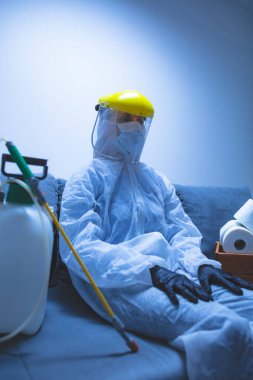 Klozet kağıdı stoğu ve koruyucu antiviral maskesi olan kişi, kask, kimyasal dezenfekte spreyi ve ev izolasyonu şişesi..