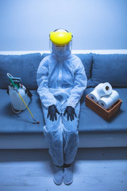 Klozet kağıdı stoğu ve koruyucu antiviral maskesi olan kişi, kask, kimyasal dezenfekte spreyi ve ev izolasyonu şişesi..