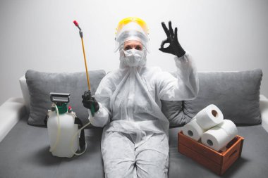 Klozet kağıdı stoğu ve koruyucu antiviral maskesi olan kişi, kask, kimyasal dezenfekte spreyi ve ev izolasyonu şişesi..