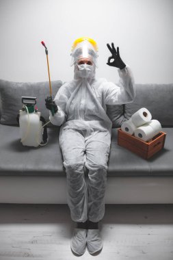 Klozet kağıdı stoğu ve koruyucu antiviral maskesi olan kişi, kask, kimyasal dezenfekte spreyi ve ev izolasyonu şişesi..