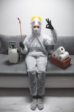 Klozet kağıdı stoğu ve koruyucu antiviral maskesi olan kişi, kask, kimyasal dezenfekte spreyi ve ev izolasyonu şişesi..