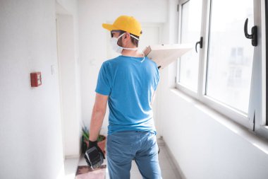 Koruyucu tıbbi maskeli teslimatçı elinde pizza kutusu tutuyordu. Virüsler ve salgınlarla dolu günler, evinize yiyecek teslimatı..