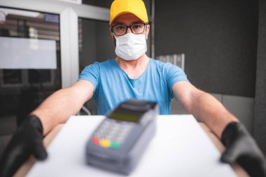 Koruyucu tıbbi maskeli teslimatçı elinde pizza kutusu tutuyordu. Virüsler ve salgınlarla dolu günler, evinize yiyecek teslimatı..