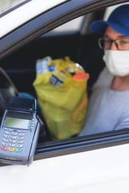 Koruyucu maskeli ve eldivenli teslimatçı adam tecrit ve salgın sırasında market alışverişlerini temizliyor..