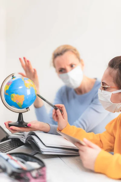 Child home studying education, homeschooling, with private tutor / mother with protective mask in the time of viruses, flu and seasonal pandemic, healthy approach in social contact.