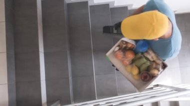 Koruyucu maskeli teslimatçı. Bakkaliye ve POS 'la dolu bir çanta tutuyor..