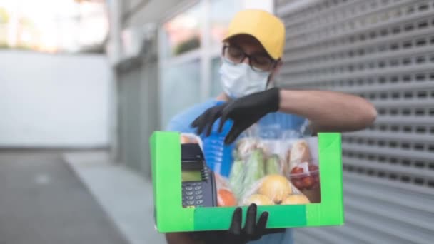非接触決済のための食料品やPosと保護マスク保持ボックス バッグ付き配達男 — ストック動画