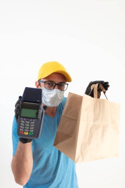 Koruyucu maskeli teslimatçı. Bakkaliye ve POS 'la dolu bir çanta tutuyor..