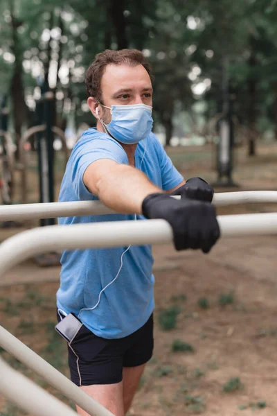 Deportista Con Máscara Médica Guantes Smartphone Auriculares Trabajando Trotando Entorno —  Fotos de Stock