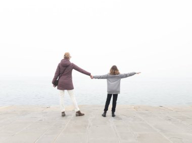 Anne ve kız deniz kıyısında uzak sisli ufka bakıyorlar..