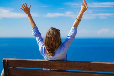 Okyanus / denizin üzerindeki uçurum kenarında oturan kadın..