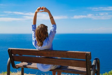 Okyanus / denizin üzerindeki uçurum kenarında oturan kadın..