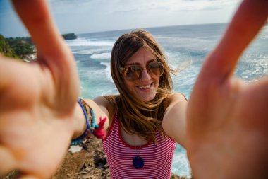 Kadın turist akıllı telefonuyla tropik bir adada fotoğraf çekiyor..