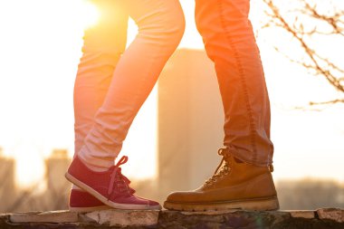 Gün batımında ve gün doğumunda bir çiftin bacaklarının siluetleri..