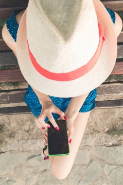 Parkta akıllı telefon kullanan genç bir kadın..