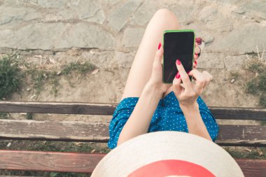 Parkta akıllı telefon kullanan genç bir kadın..