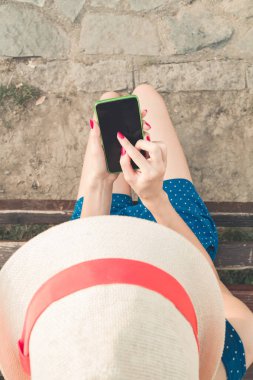 Parkta akıllı telefon kullanan genç bir kadın..