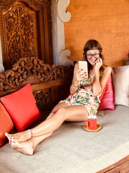 现代年轻女子使用手机 在阳台沙发上喝咖啡 — 图库照片