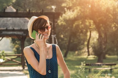 Parkta akıllı telefon kullanan genç bir kadın..