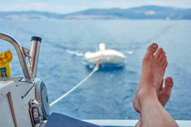 Yelkenli teknede sakin denizin tadını çıkaran bir adam.