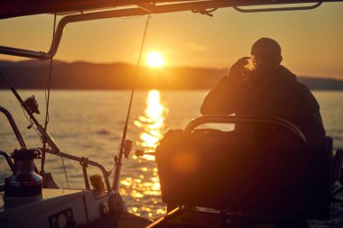 Yelkenli yelkenli yelkenli yelkenli yelkenli şafakta / alacakaranlık vakti açık denizde.