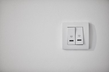 Beyaz bir duvarda modern ışık düğmesi.