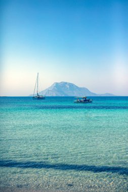 Uzak ada cennetinde, canlı renklerle yelkenli bir tekne..