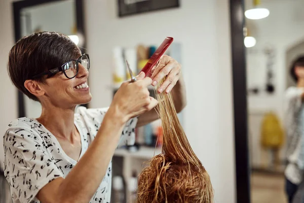 Hair dresser cutting hair in a saloon.