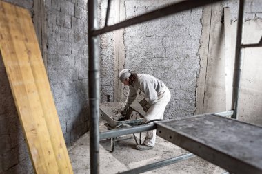 Gerçek inşaat işçisi yeni evin içinde bir duvar yapma.