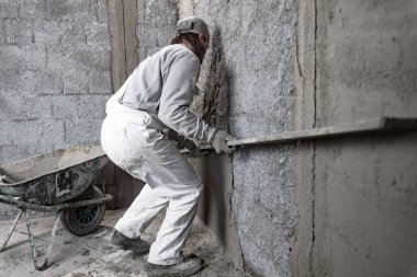 Gerçek inşaat işçisi yeni evin içinde bir duvar yapma.