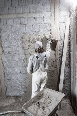 Gerçek inşaat işçisi yeni evin içinde bir duvar yapma.