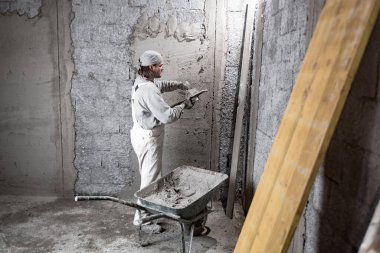 Gerçek inşaat işçisi yeni evin içinde bir duvar yapma.