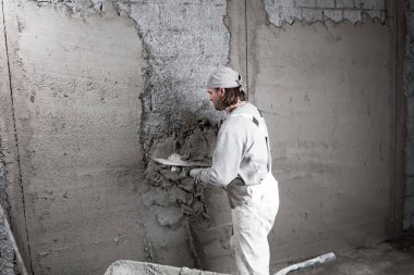 Gerçek inşaat işçisi yeni evin içinde bir duvar yapma.