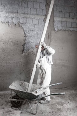 Gerçek inşaat işçisi yeni evin içinde bir duvar yapma.