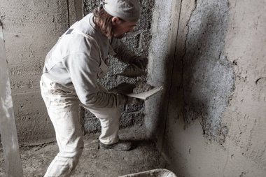 Gerçek inşaat işçisi yeni evin içinde bir duvar yapma.