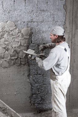 Gerçek inşaat işçisi yeni evin içinde bir duvar yapma.