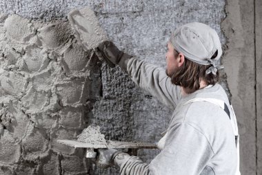 Gerçek inşaat işçisi yeni evin içinde bir duvar yapma.